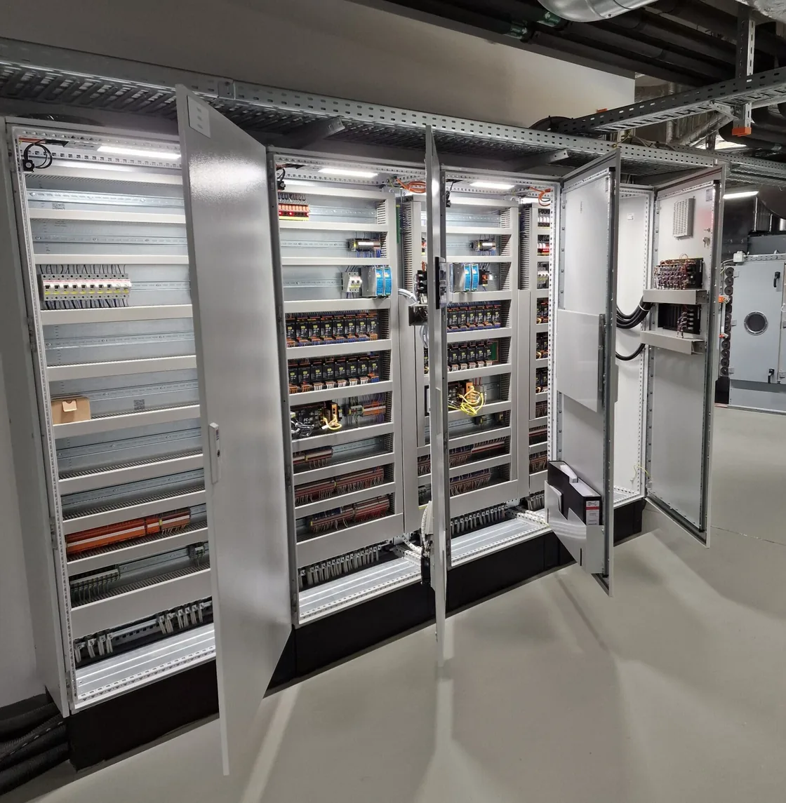 Geöffnete Schaltschränke mit Steuerungs- und Automatisierungstechnik in einem Technikraum